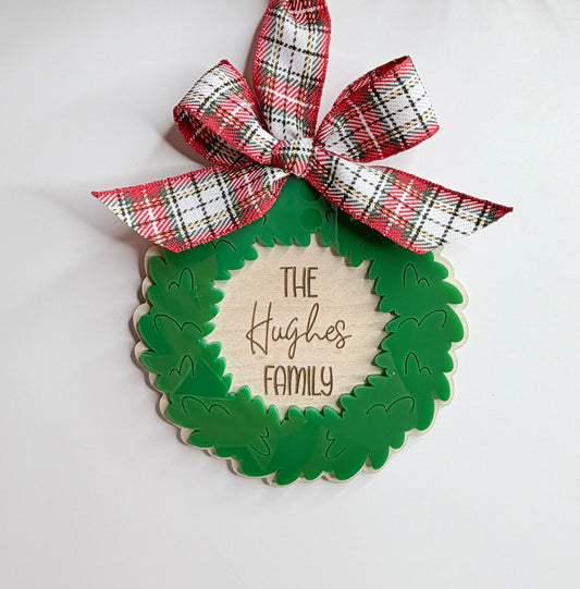 Green wreath-shaped ornament with 'The Hughes Family' text and plaid ribbon on a white background